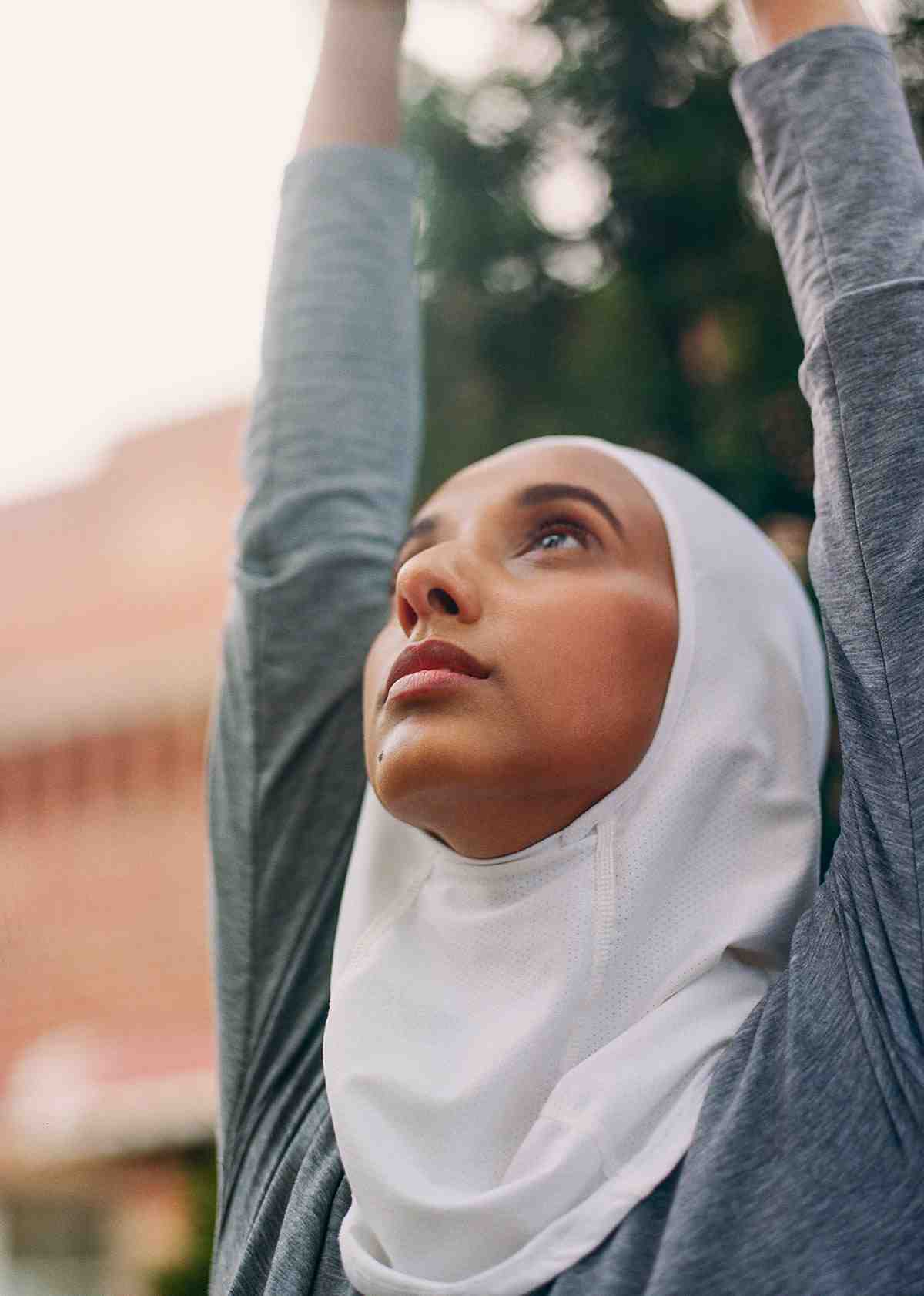 Woman in a hijab reaching toward the sky in a yoga pose